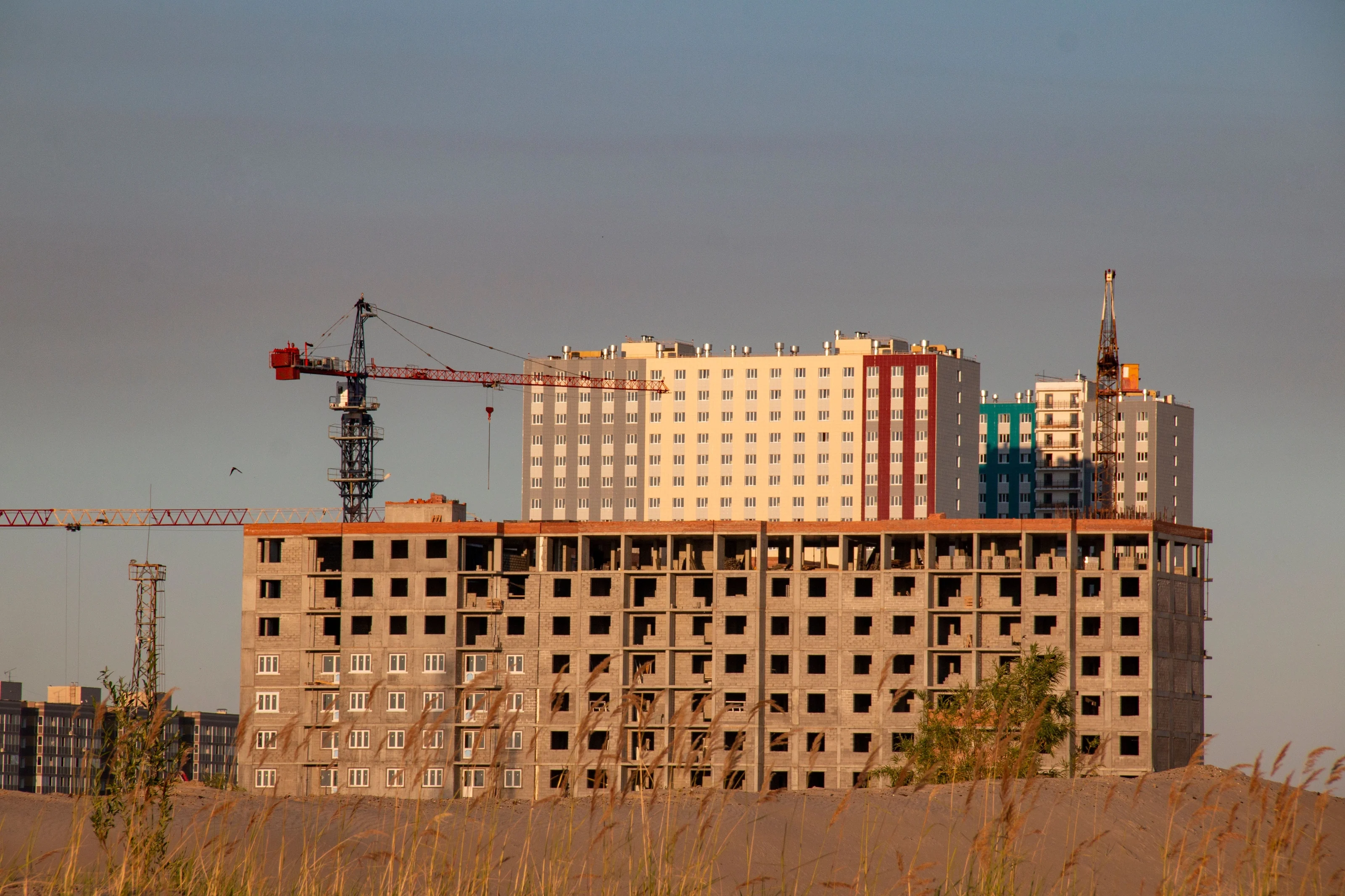 Cranes above an active multi-storey construction site — illustrative sector photograph