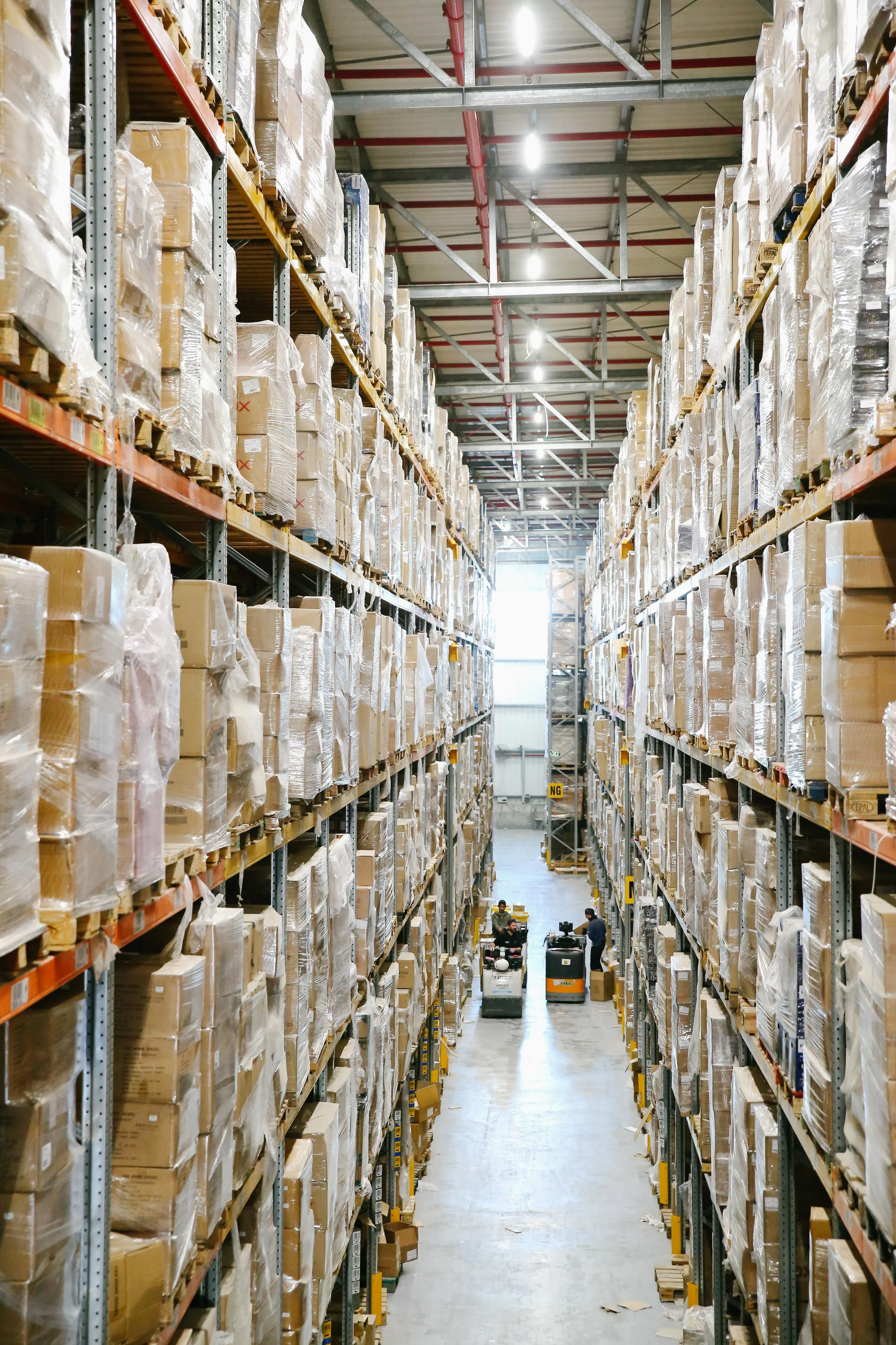 Warehouse aisle with packaged goods on tall storage shelves — illustrative sector photograph